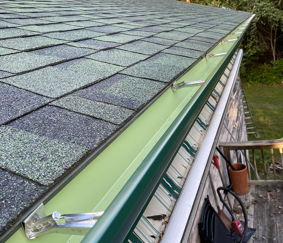 vermont-gutter-company-burlington-vt-6 Close‑up of the top of a shingle roof with gutters attached on a home in Burlington, VT.