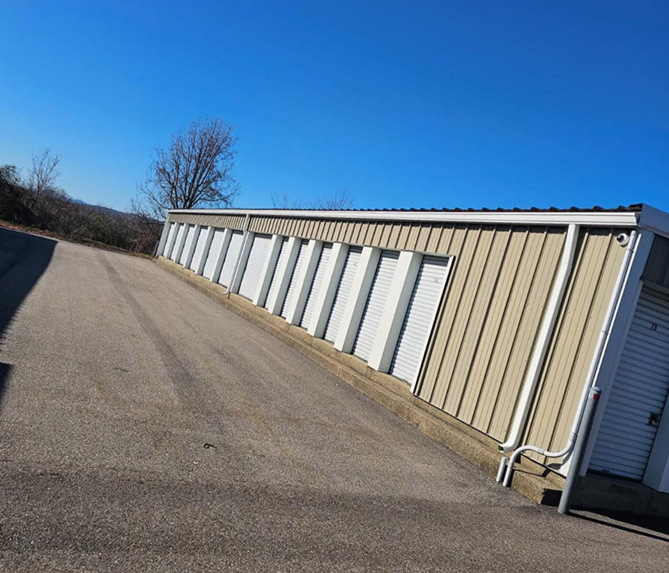 vermont-gutter-company-middlebury-vt-7 Side of a metal storage facility in Middlebury, VT, featuring white doors and newly installed white gutters.