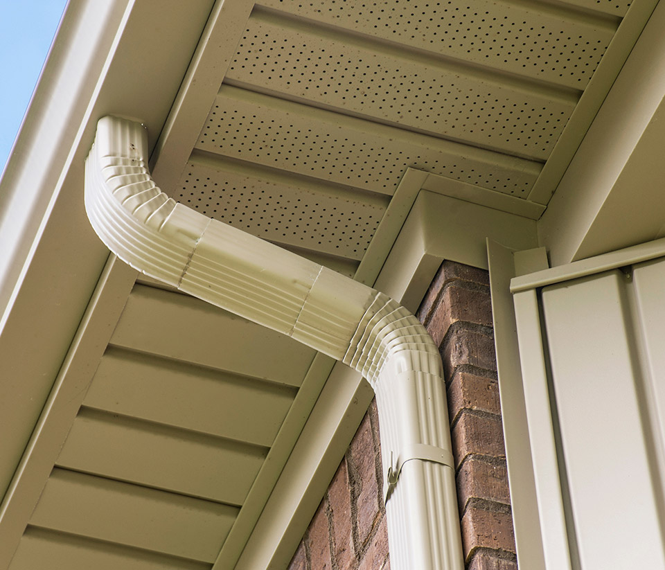 vermont-gutter-company-rutland-vt-7 Close-up view of the side of a building in Rutland, VT, showing a white gutter attached and running along the roofline.