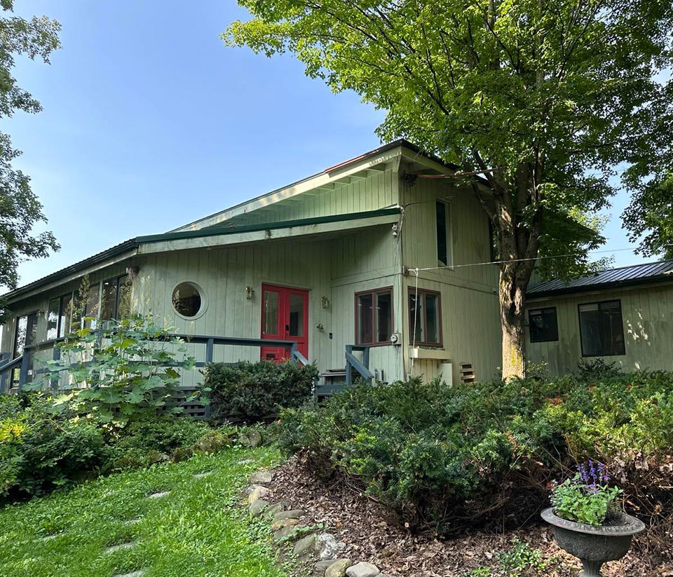 vermont-gutter-company-south-burlington-vt-3 Exterior of a home in South Burlington, VT, with green grass, shrubs in the front yard, and a slanted roof.