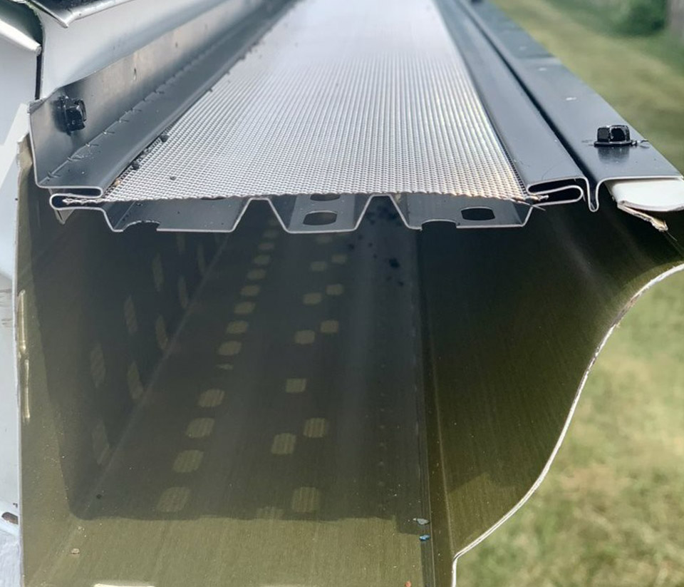 vermont-gutter-company-williston-vt-6 Close-up of a gutter on the side of a home in Williston, VT, showing a leaf guard installed on top.